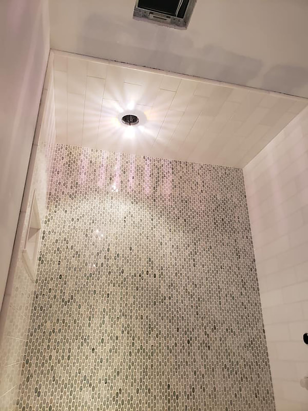 Blue glass mosaic accents in white subway tile sho with light installation