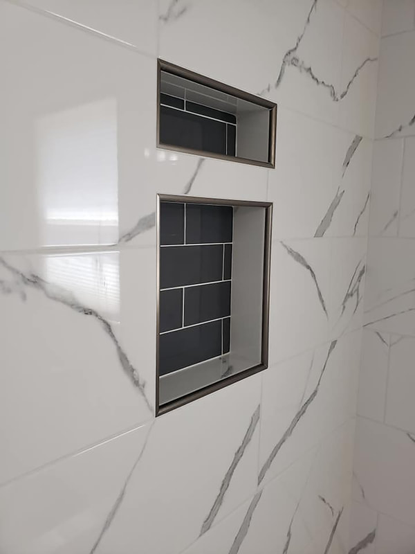 Close up of shower niche in gray subway tile and stainless steel