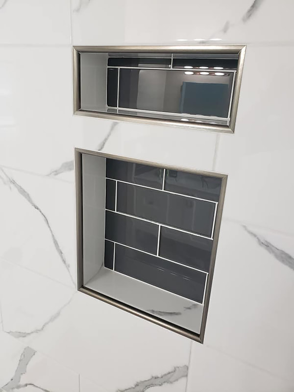 Close up of shower niche in gray subway tile and stainless steel