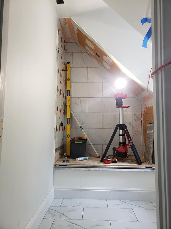 White marble tile installation in angled shower