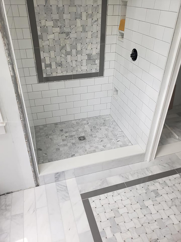 Walk in shower with basket weave tile detail followed through onto bathroom floor